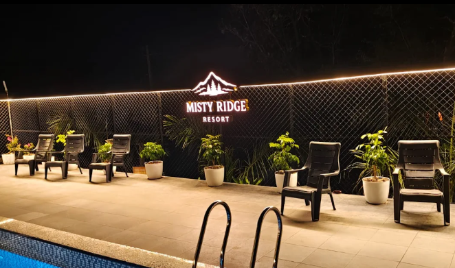 Misty Ridge Resort poolside deck with illuminated resort sign and seating